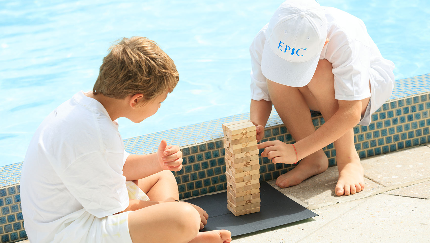 two kids playing Jenga by the pool